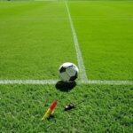 Campo de futebol com apito e cartões de árbitro, representando anúncio da CBF sobre salários para árbitros profissionais.