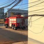 Residência em Brasília com fiação elétrica exposta, alertando para risco de incêndios no verão no DF, com caminhão de bombeiros ao fundo.