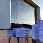Edifício do TJDFT em Brasília com documentos judiciais, simbolizando 607 mil processos julgados e alta demanda.