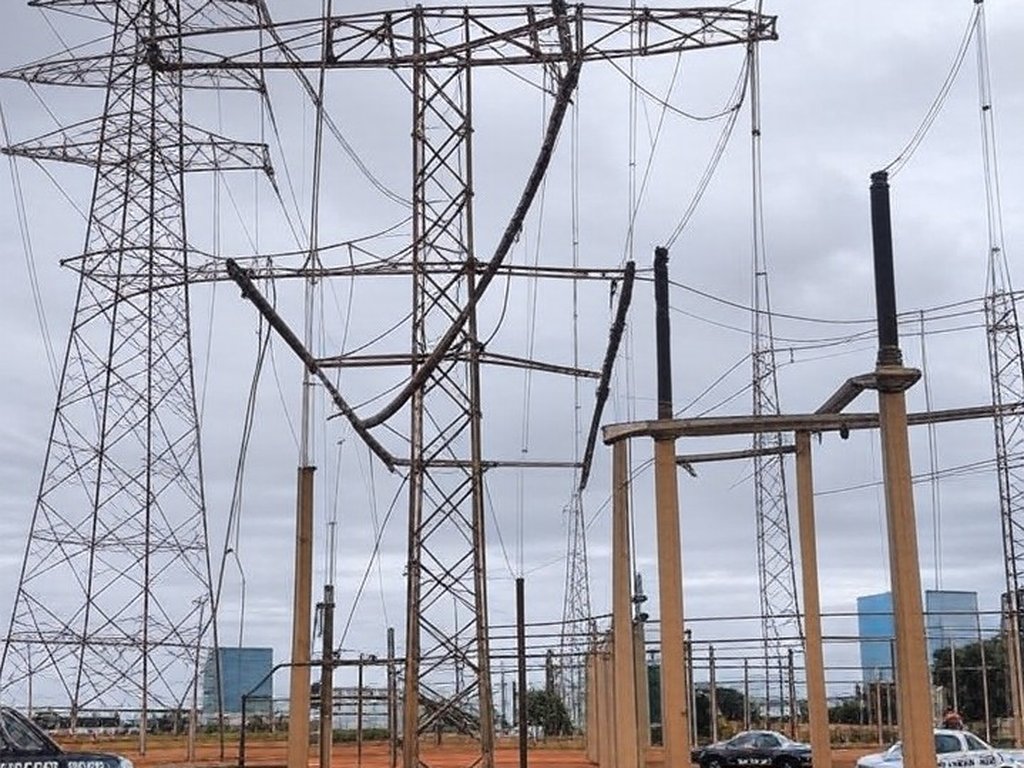 Subestação elétrica no DF com cabos danificados por tentativa de furto e viaturas policiais ao fundo.