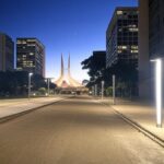 Rua noturna em Brasília com luminárias reformadas pela CEB IPes, promovendo economia de energia no DF.