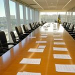 Sala de reuniões governamental em Brasília com documentos sobre reforma tributária e bandeiras brasileiras.