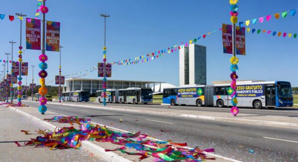 Ônibus do transporte público em Brasília durante o Carnaval, com confetes e avenida larga, representando acessos gratuitos no DF.