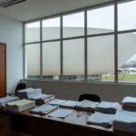 Edifício governamental em Brasília com formulários de inscrição, relógio e barreiras simbólicas para conselho da Caesb e Adasa.