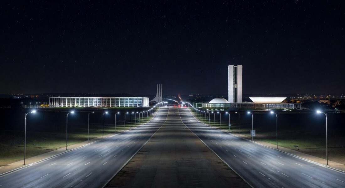 Avenida noturna em Brasília iluminada por postes de LED modernos no Distrito Federal.