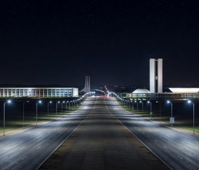 Avenida noturna em Brasília iluminada por postes de LED modernos no Distrito Federal.