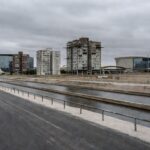 Obra hídrica tardia no Lago Sul, DF, com reservatórios e tubulações em paisagem urbana negligenciada.