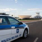 Viatura da PMDF em Brasília com smartphone no painel, ilustrando app Nexus para relatórios policiais.