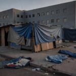 Rua urbana brasileira com abrigos improvisados simbolizando crítica à internação compulsória de moradores de rua